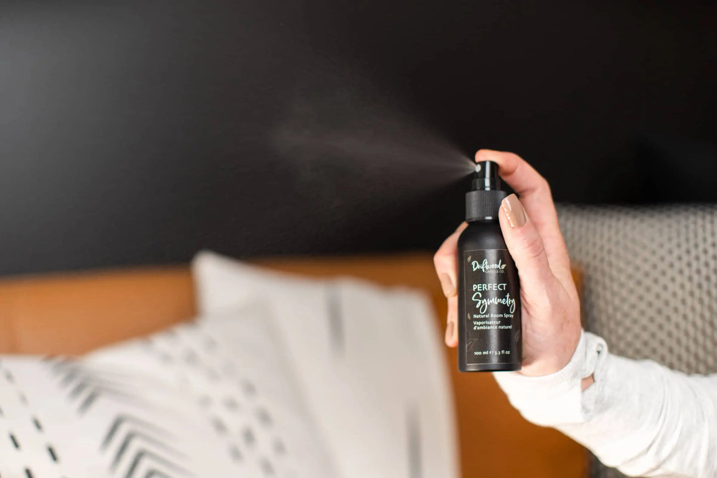 Model is spraying sample bottle of Driftwood Candle Co. Room spray. Mist is visible in photo demonstrating the power of the spray.