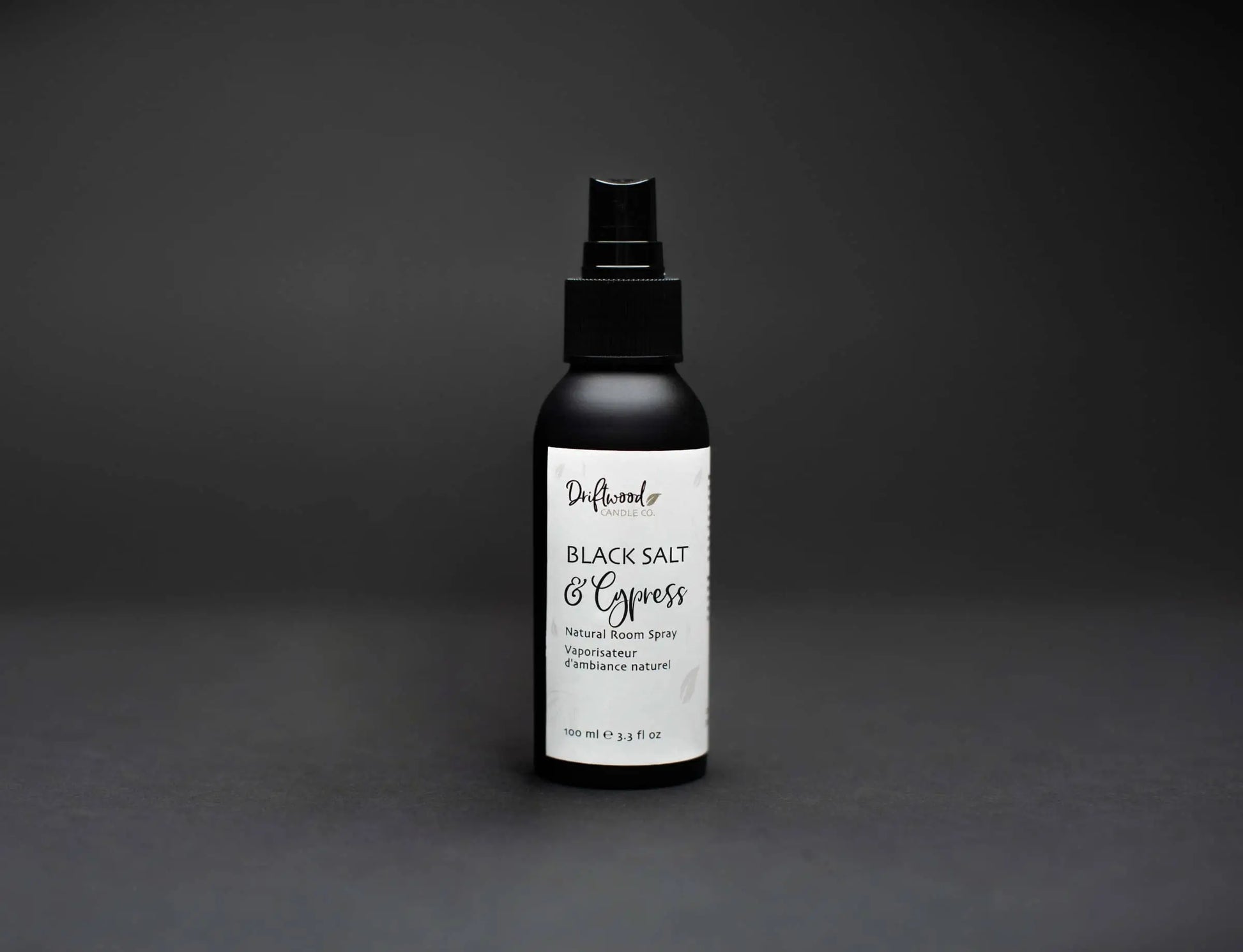 Image of Driftwood Candle Co. Black Salt & Cypress scented room spray.  Black bottle on a black backdrop for a moody image.